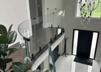Curved glass stair railing with black posts in a modern foyer